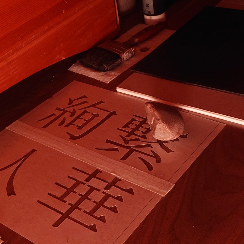 Handmade Stencil for artwork featuring four Japanese Kanji: 絢 (color), 繋 (connection), 人 (people), and 華 (to blossom), with a paintbrush