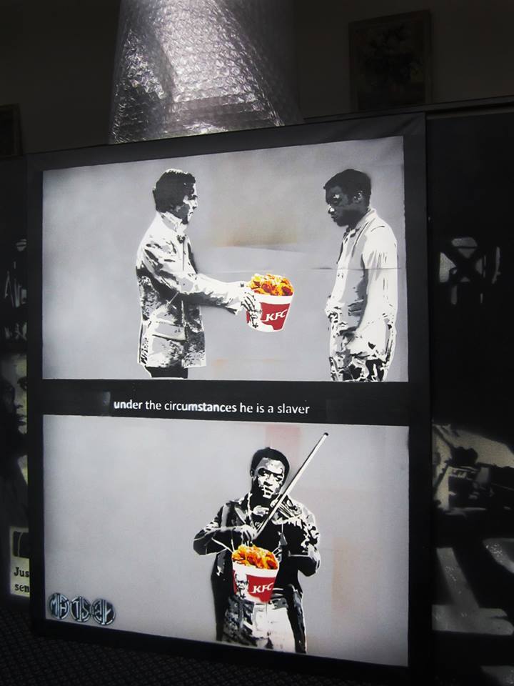 a stencil graffiti painting of Benedict Cumberbatch handing  Chiwetel Ejiofor a bright red bucket of KFC which links to a video of a local graffiti war in Birmingham between a stencil artist and a traditional graffiti writer in Digbeth, Birmingham