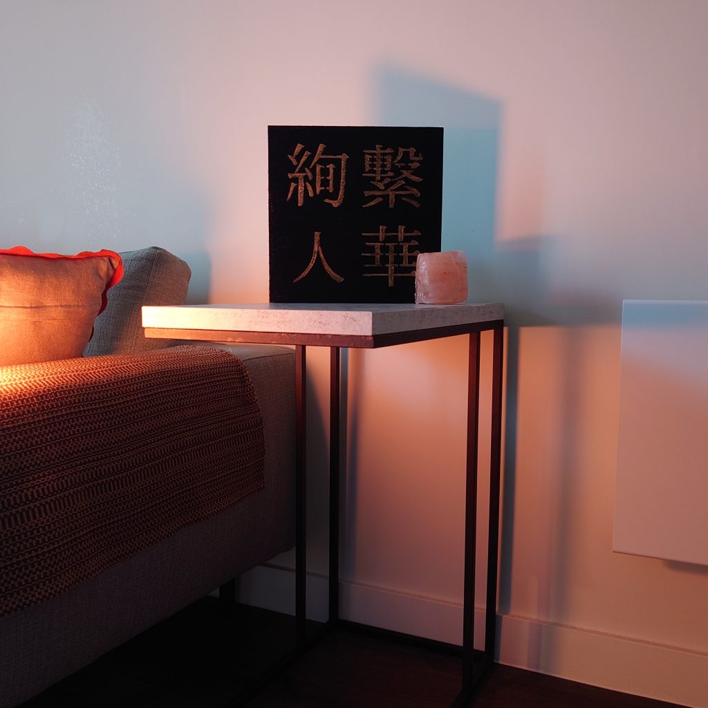 a photograph of a black and gold kanji painting standing up on a table