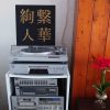 black and gold acrylic Japanese kanji paintings on record player and audio hifi stack with red flowers on the side